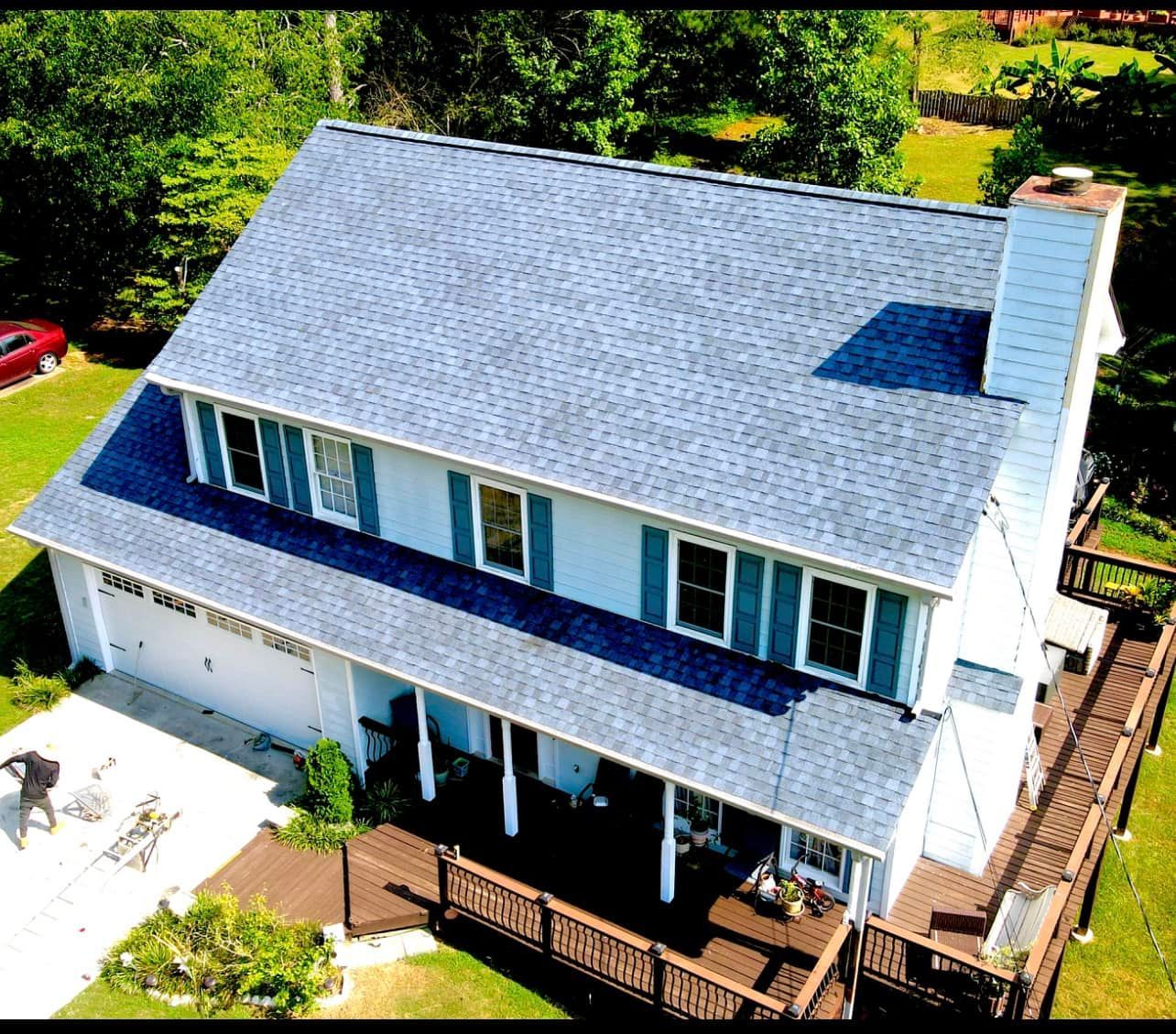 An aerial view of a large white house with a blue roof.
