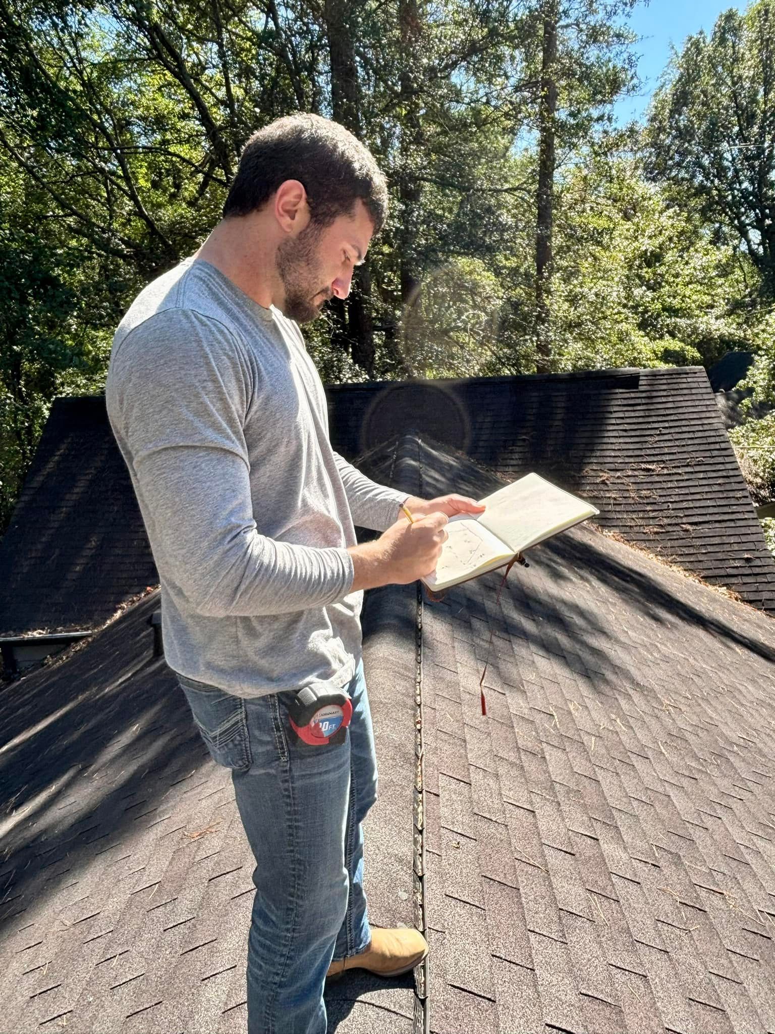 A man is standing on top of a roof looking at a piece of paper.