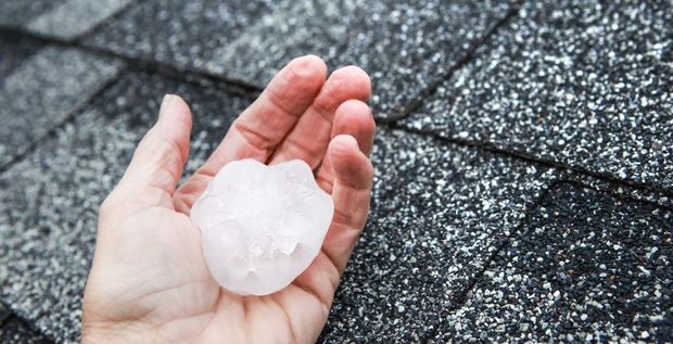 A person is holding a piece of hail in their hand.