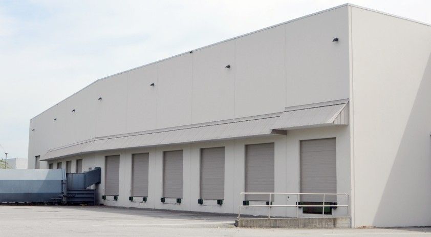 A large white warehouse with a truck parked in front of it.