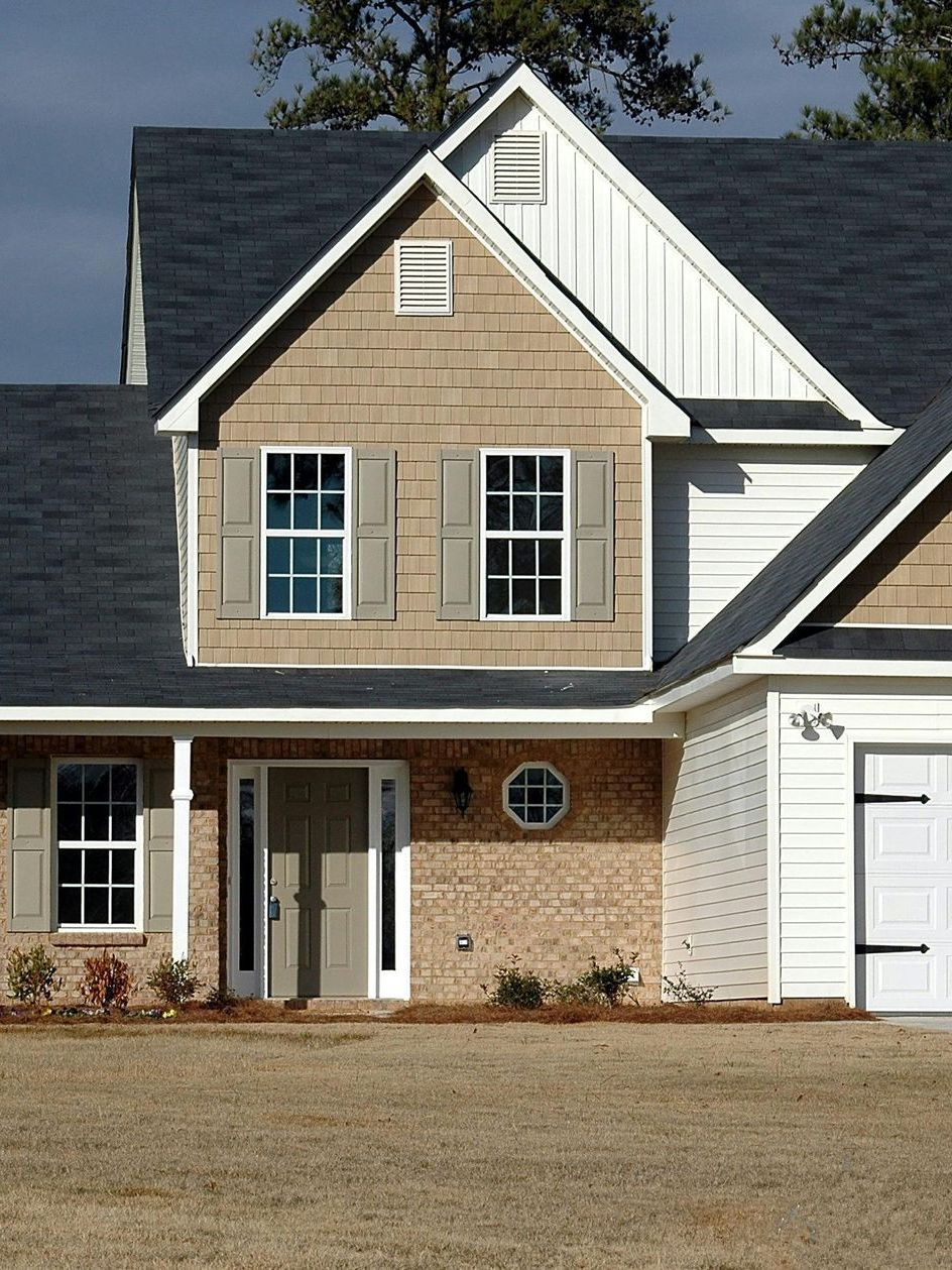 A brick house with a black roof and white trim