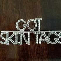 Silver “GOL SKIN TAG” text on a dark wooden background
