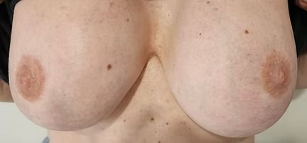 Close-up of a bare chest with two visible breasts and nipples against a plain background