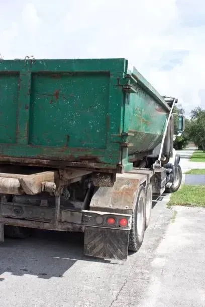 Green dump truck parked on asphalt.
