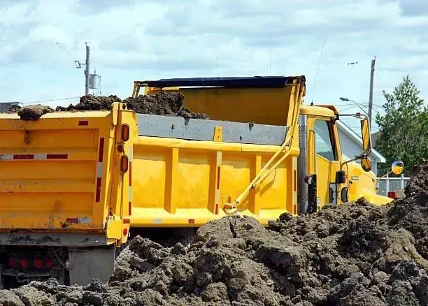 Yellow dump truck filled with dirt on a construction site.