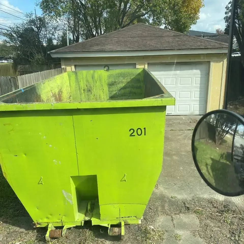 Bright green dumpster with number 201 in front of a tan garage with white doors.