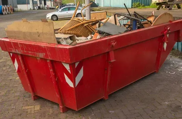 Red dumpster filled with trash, outdoors.