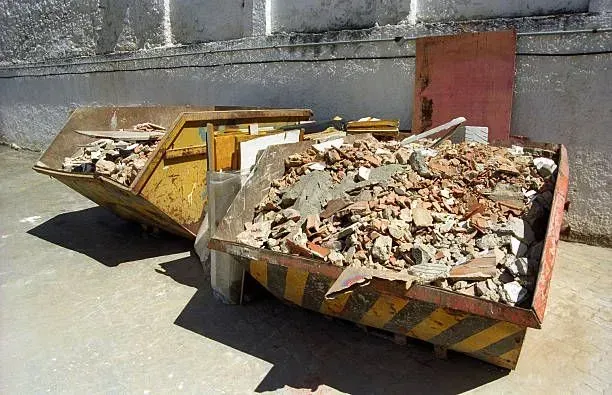 Two yellow and black striped skip bins filled with construction debris.