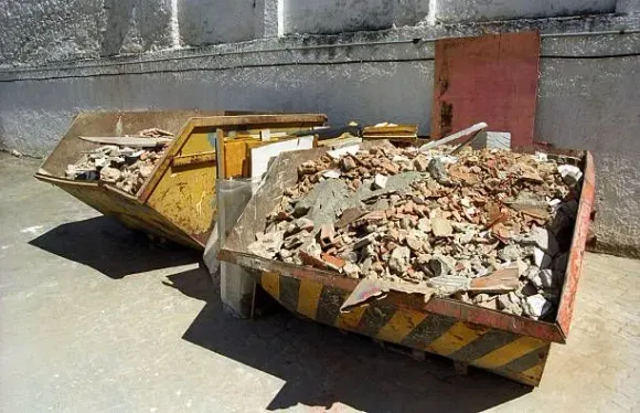 Two yellow and black striped skip bins filled with construction debris.