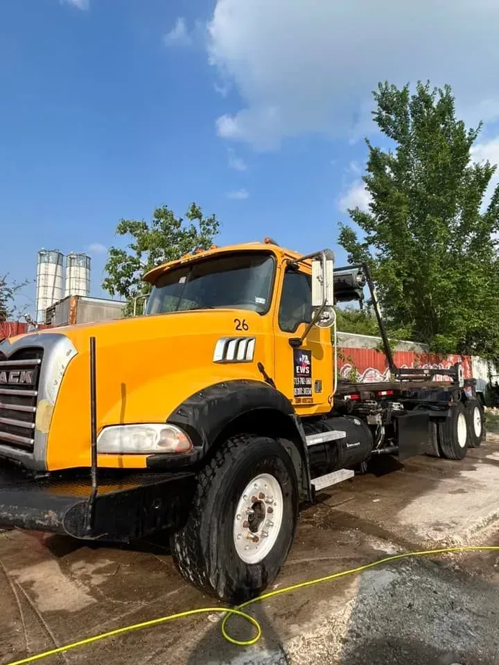 Yellow Mack truck parked outdoors on a sunny day.