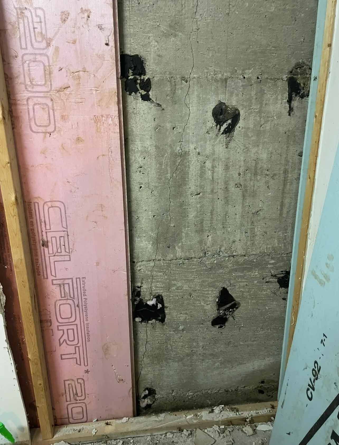 Panneau mural endommagé avec des taches noires à côté d'encadrements de porte roses et bleus