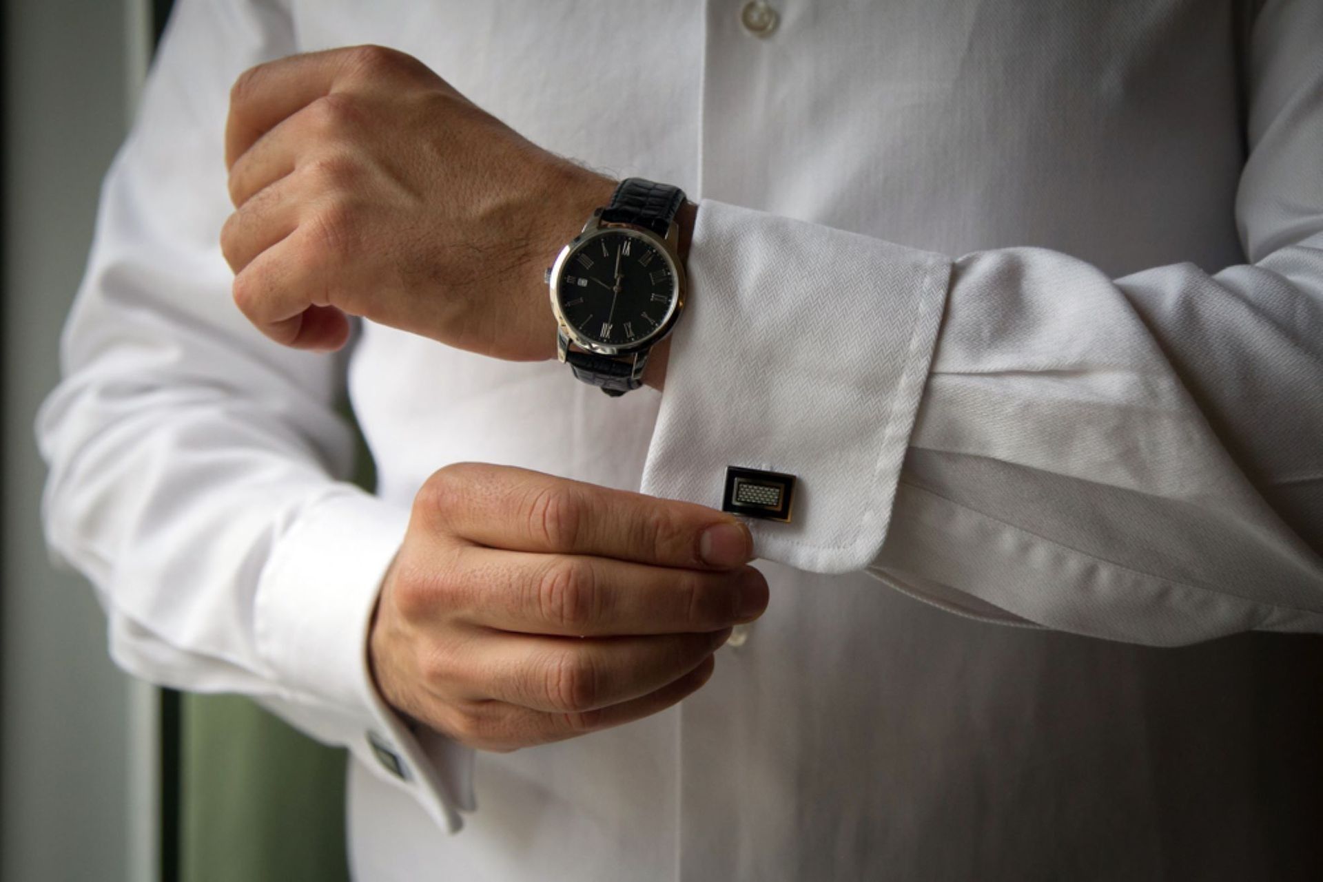 Man Adjusting Cufflinks on a White Dress Shirt, Wearing a Wristwatch — Coastal Clocks & Watches in Buddina, QLD