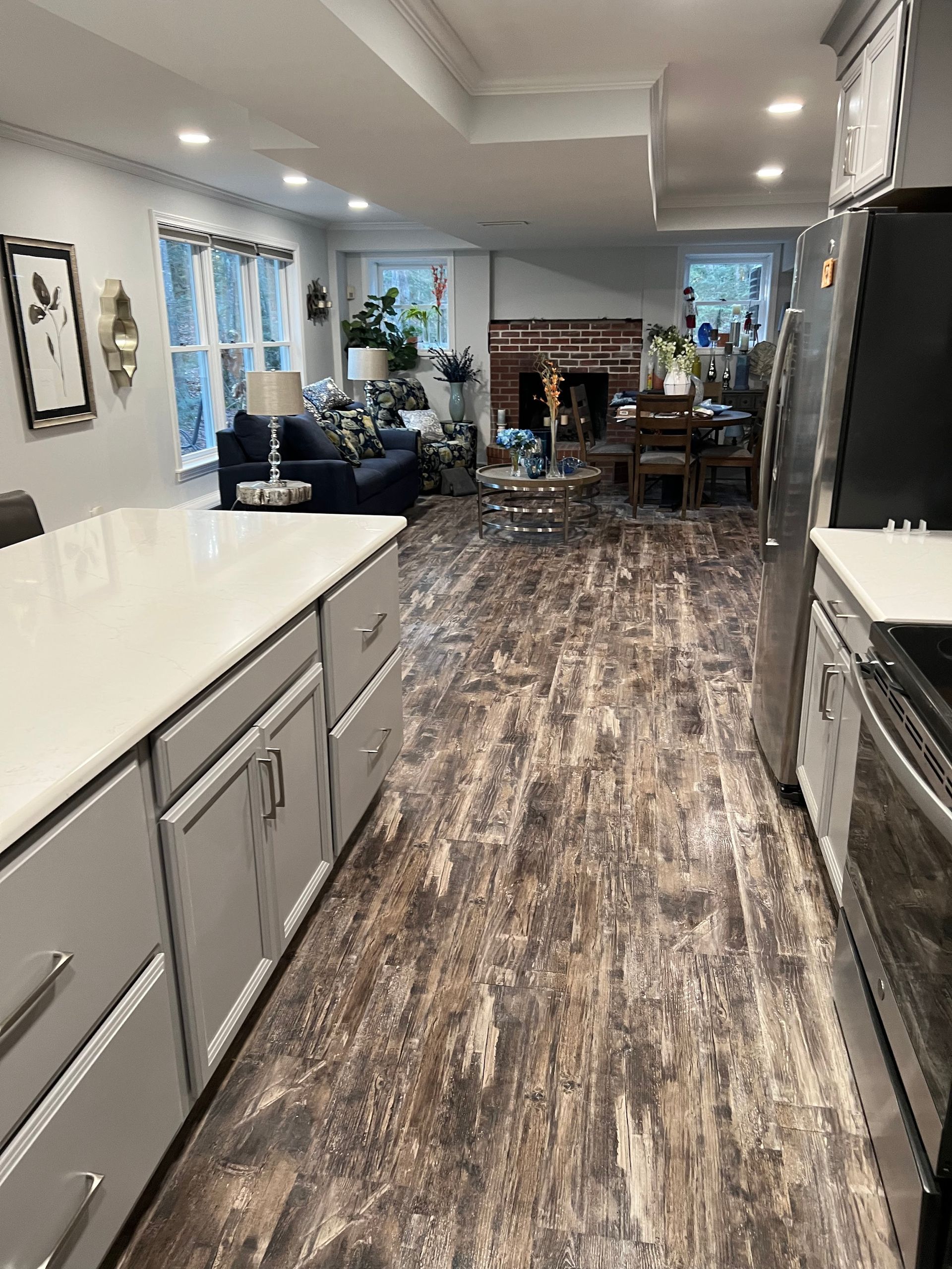 A kitchen with a long hallway leading to a living room and a fireplace.