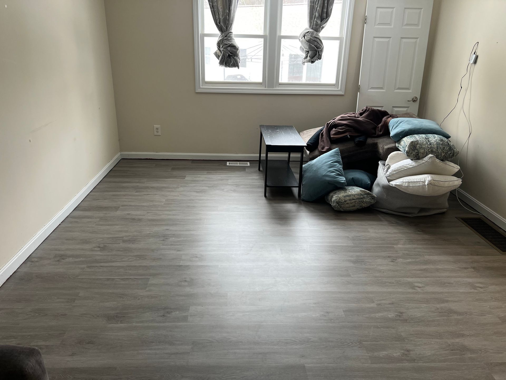 A living room with a couch and pillows on the floor.