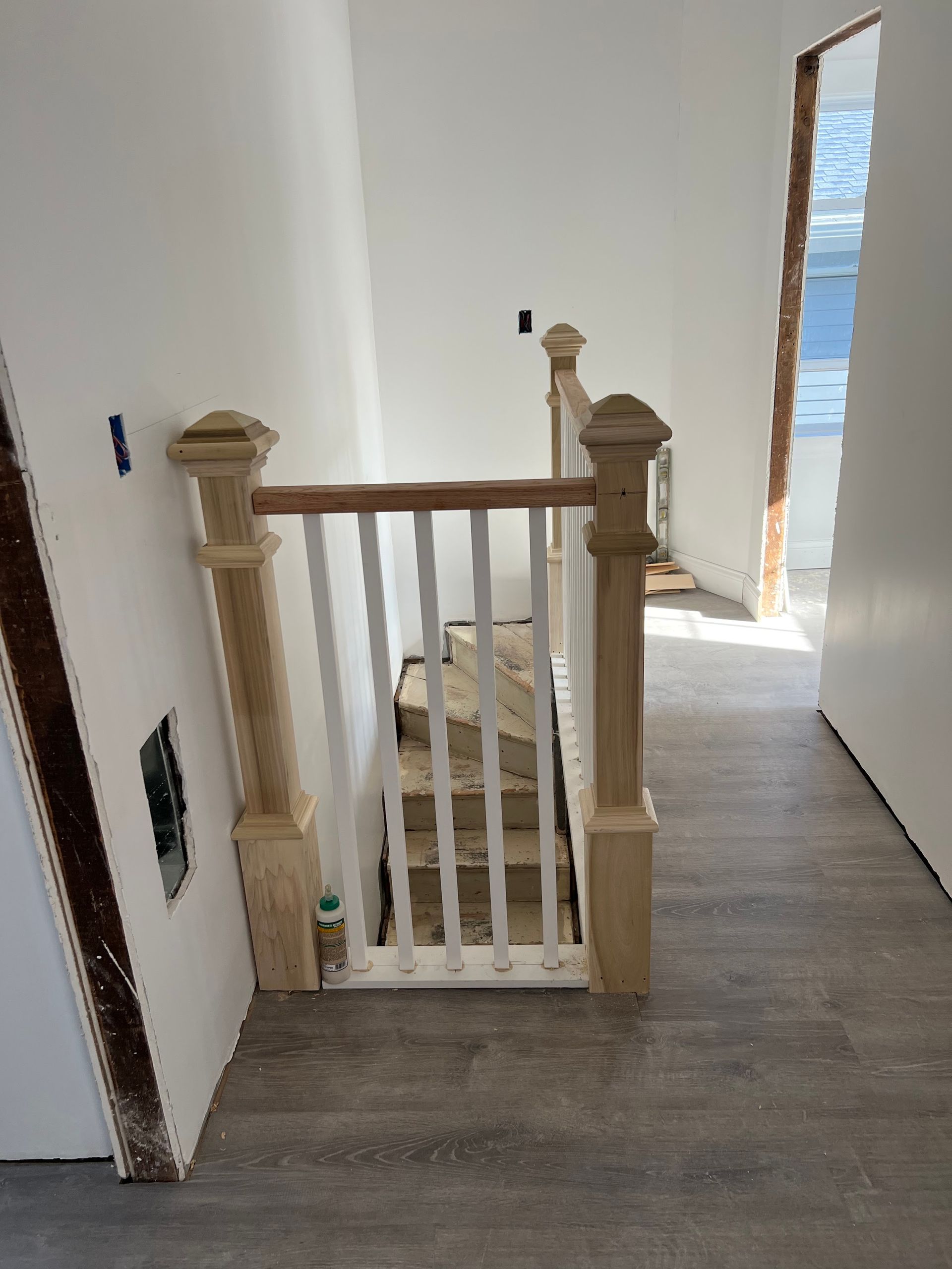 A wooden staircase with a white railing in a hallway.
