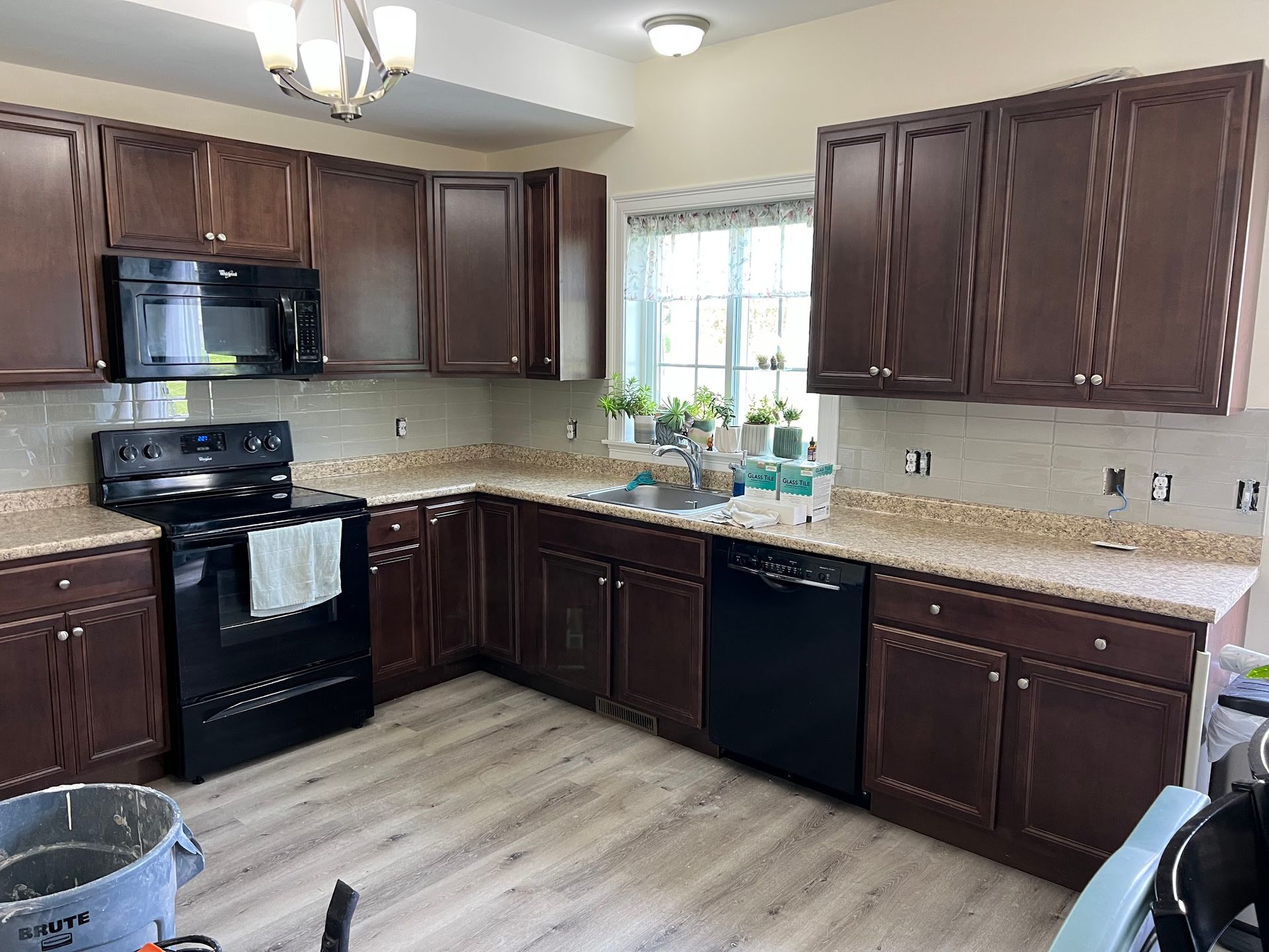 A kitchen with brown cabinets , black appliances , a stove and a sink.