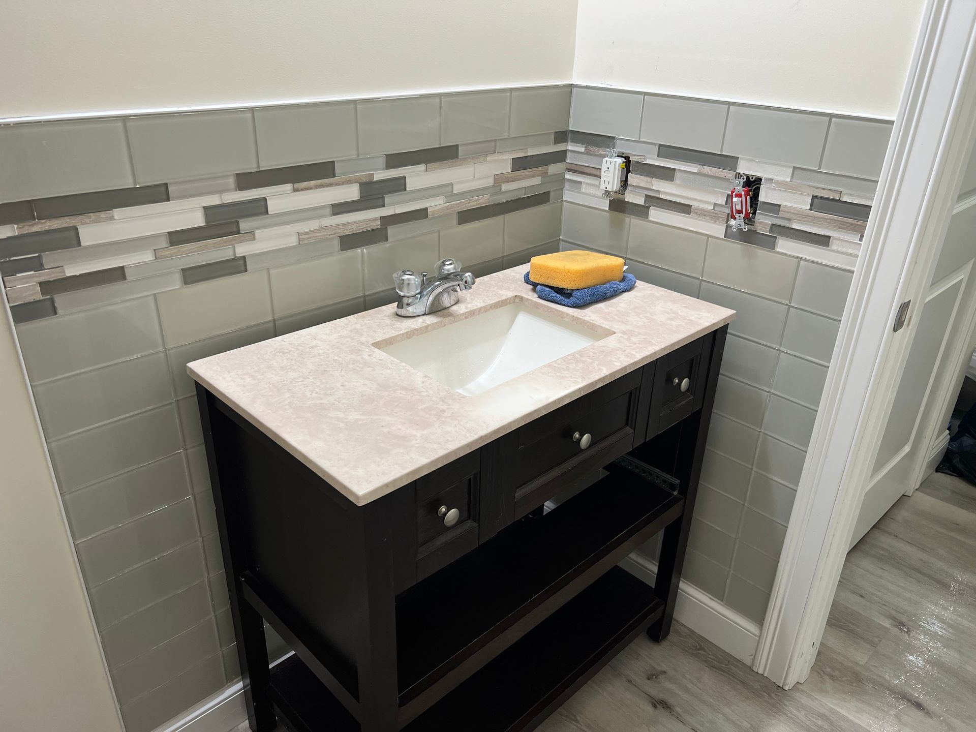 A bathroom vanity with a sink and a sponge on top of it.