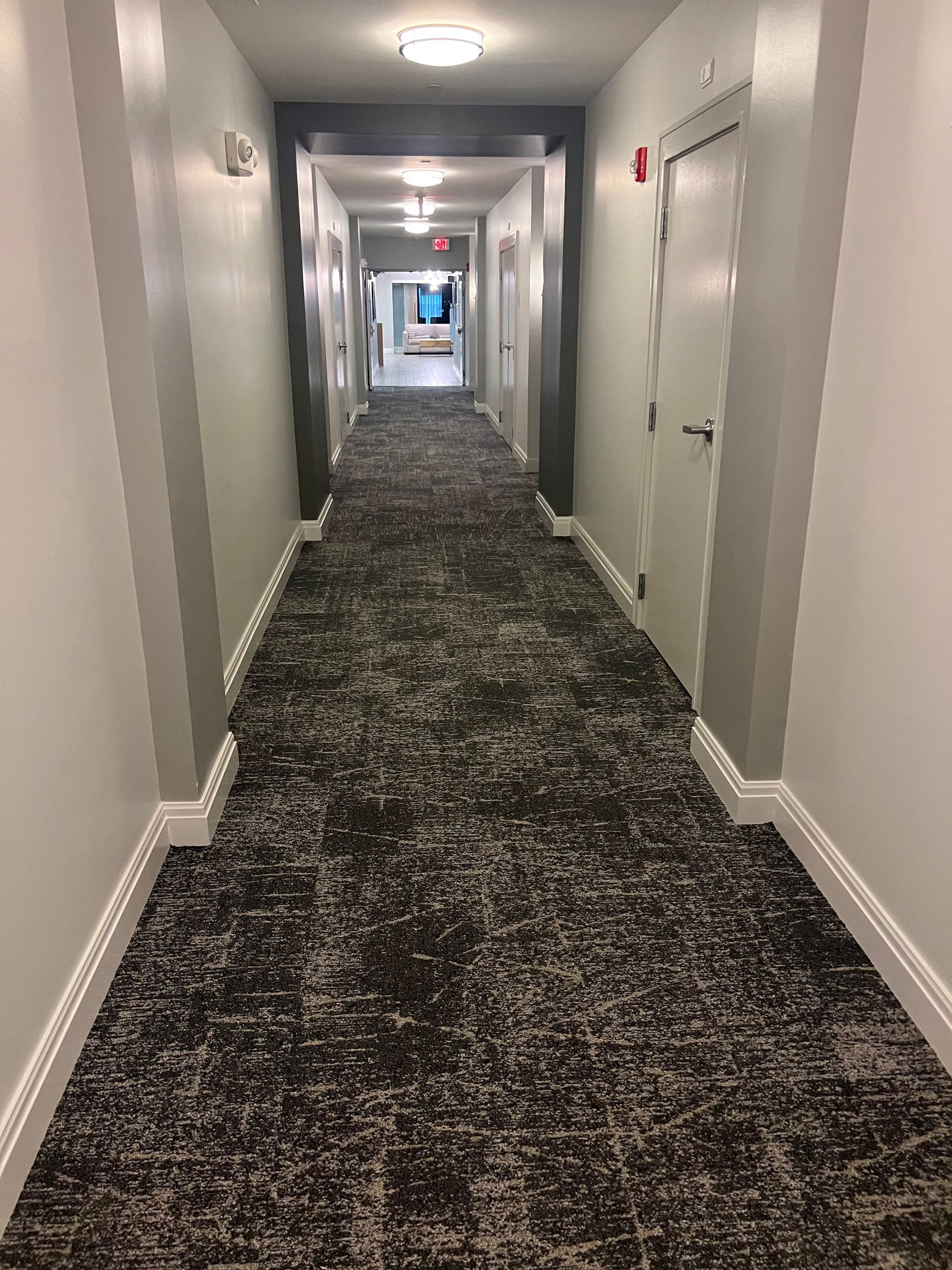 A long hallway with a black carpet and white walls.