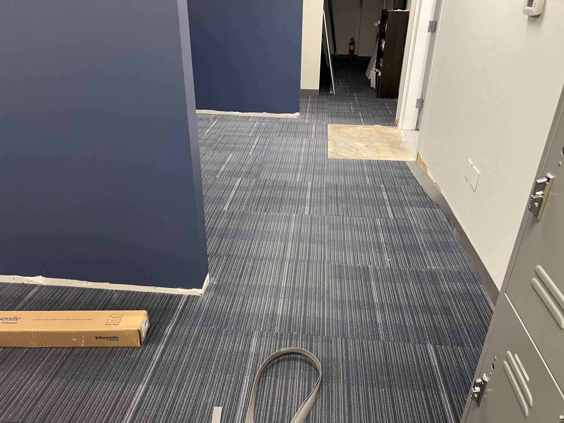 A room with a carpeted floor and a vacuum cleaner on the floor.