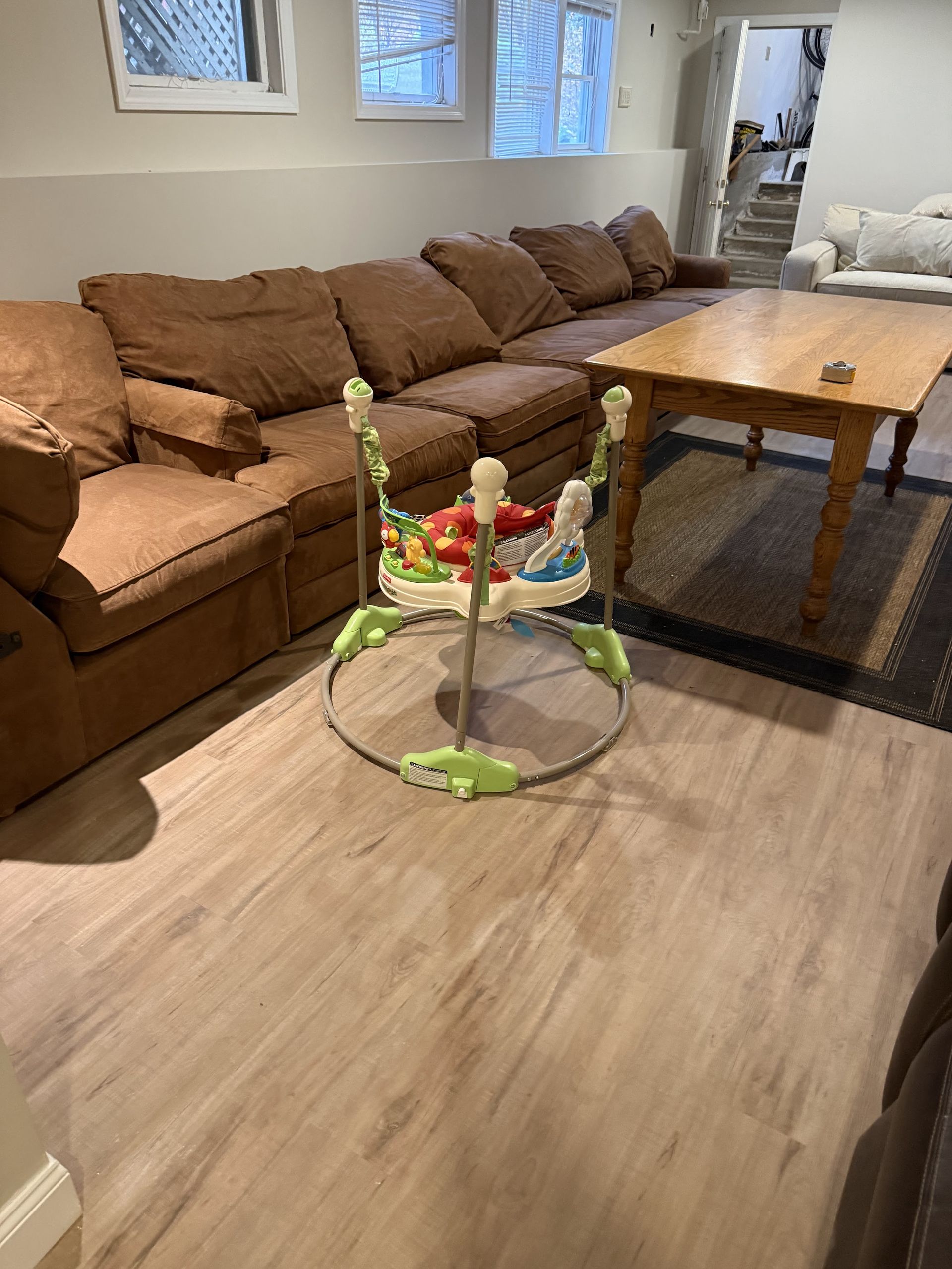 A baby walker is sitting on a wooden table in a living room.