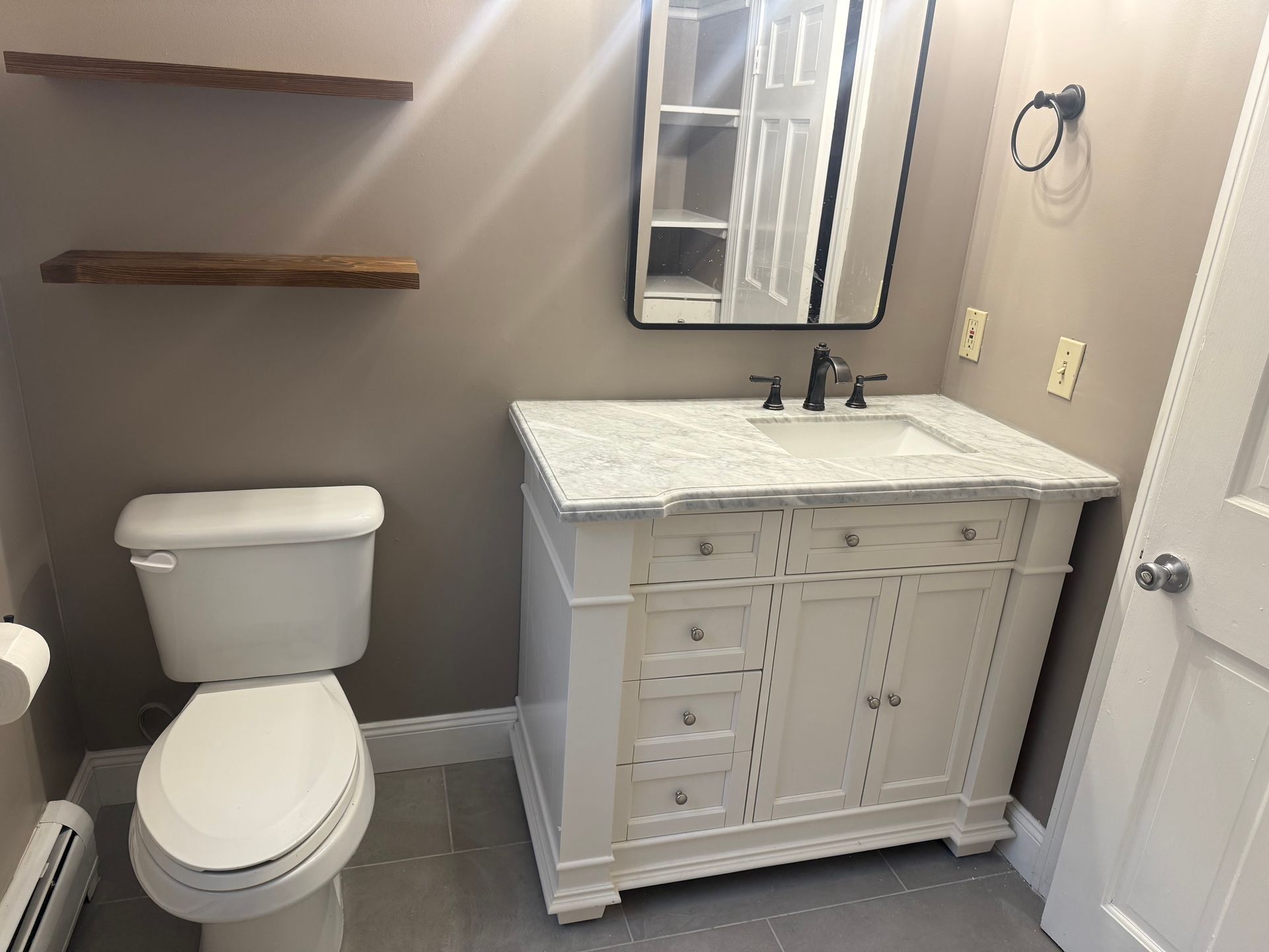 A bathroom with a toilet , sink and mirror