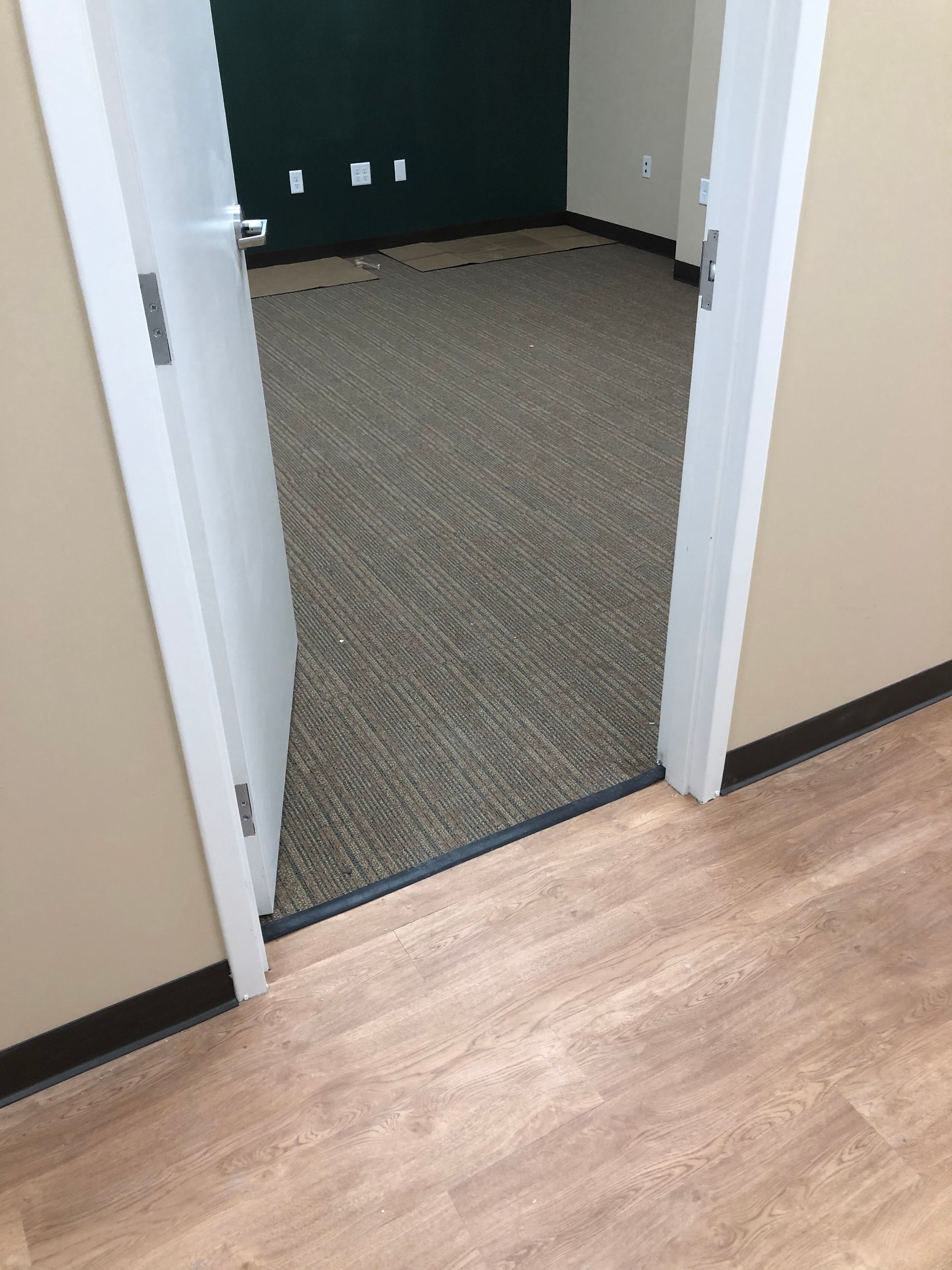 The door is open to a room with a wooden floor.