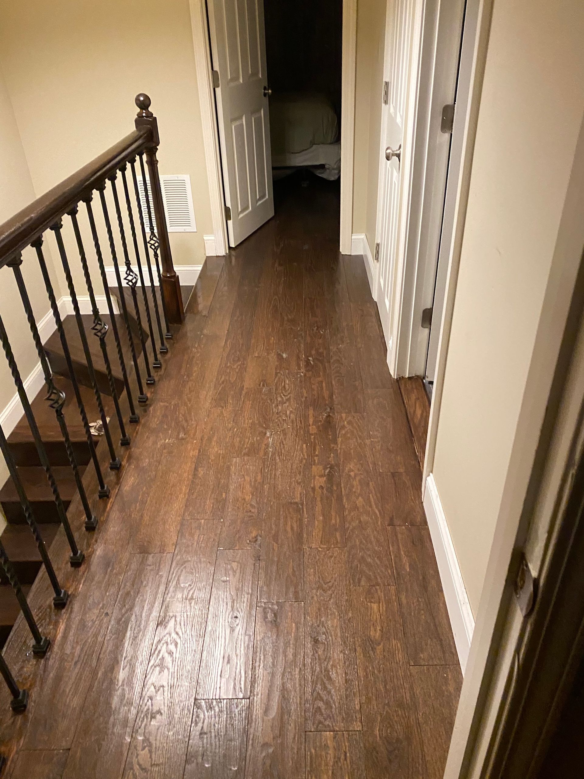 A hallway with wooden floors and stairs in a house.