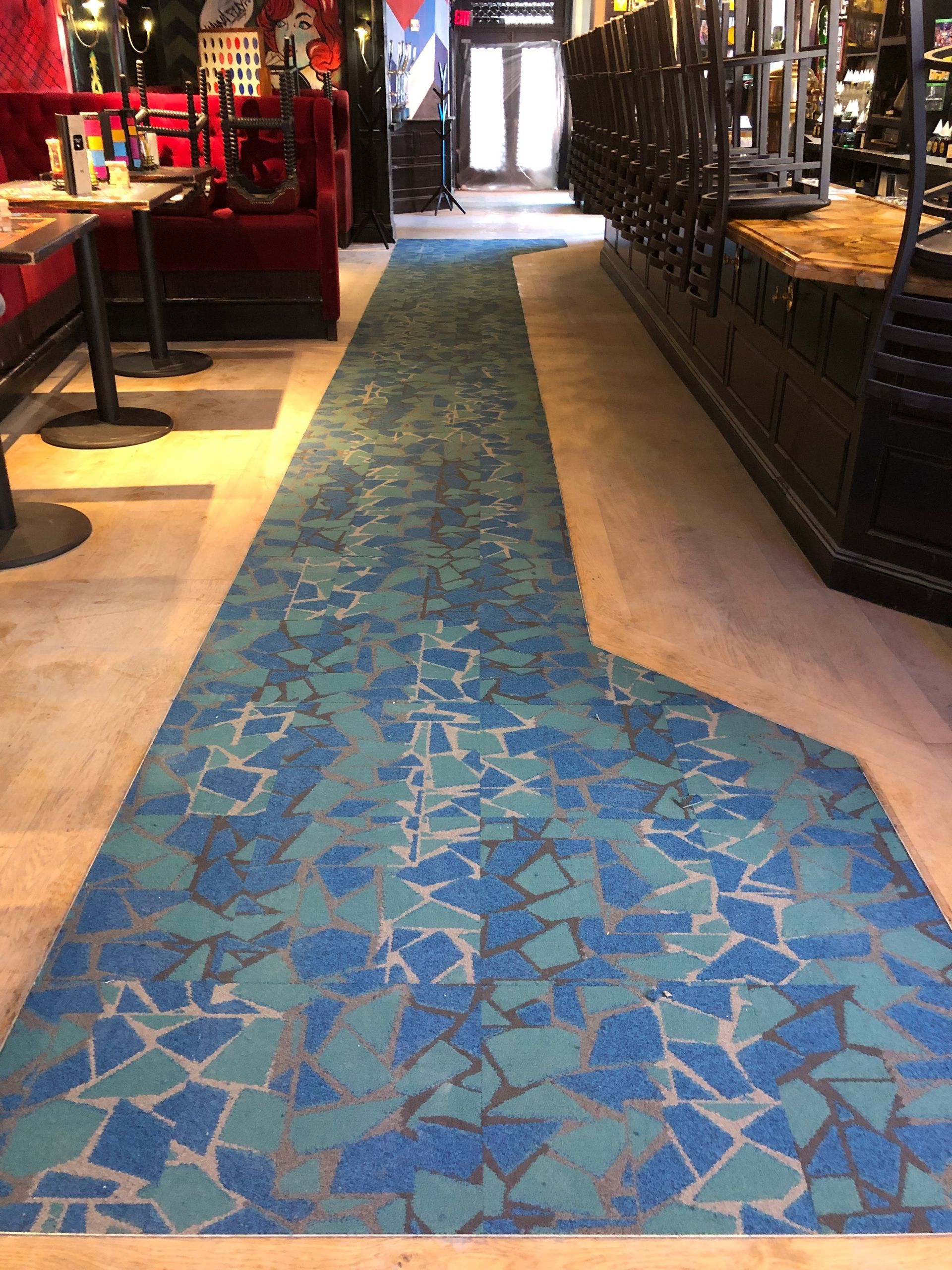 A long blue carpet is going down a hallway in a restaurant.