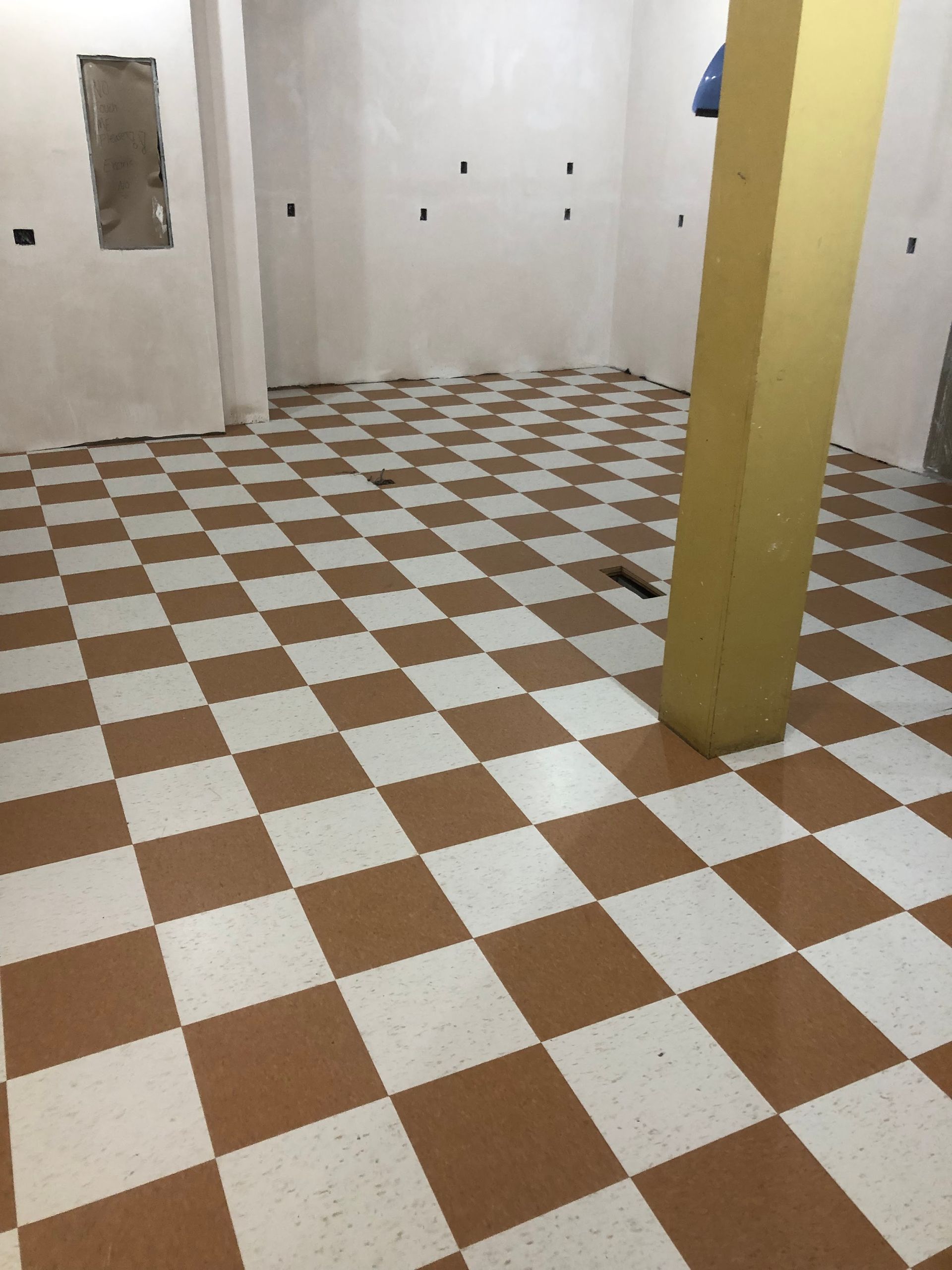 A room with a checkered floor and a yellow pillar