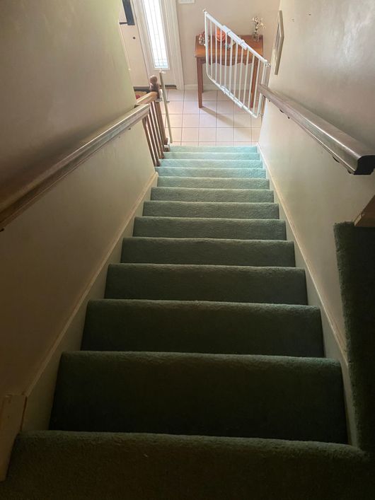 A set of stairs with green carpet and a railing
