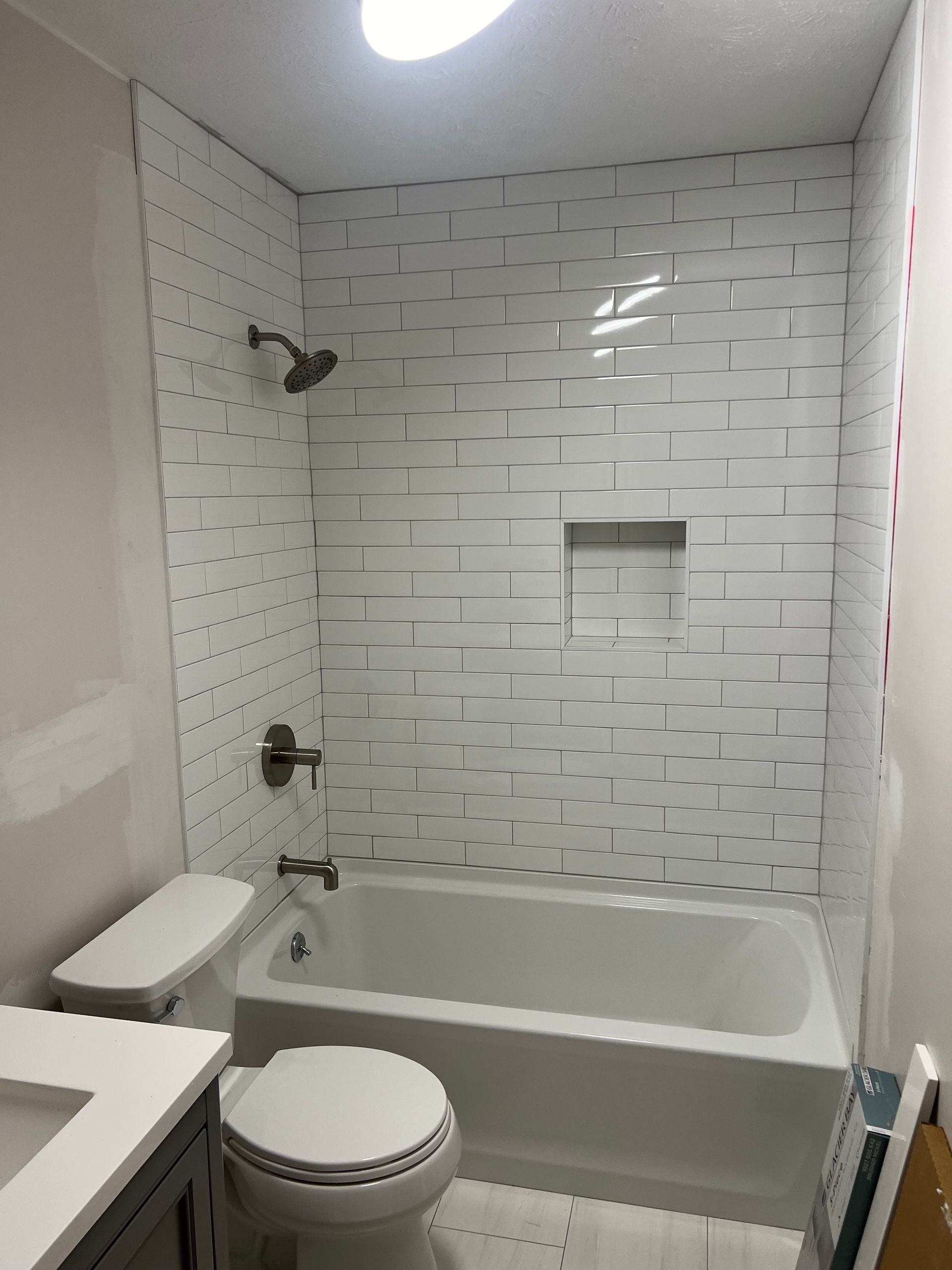 A bathroom with a toilet , tub , shower and sink.