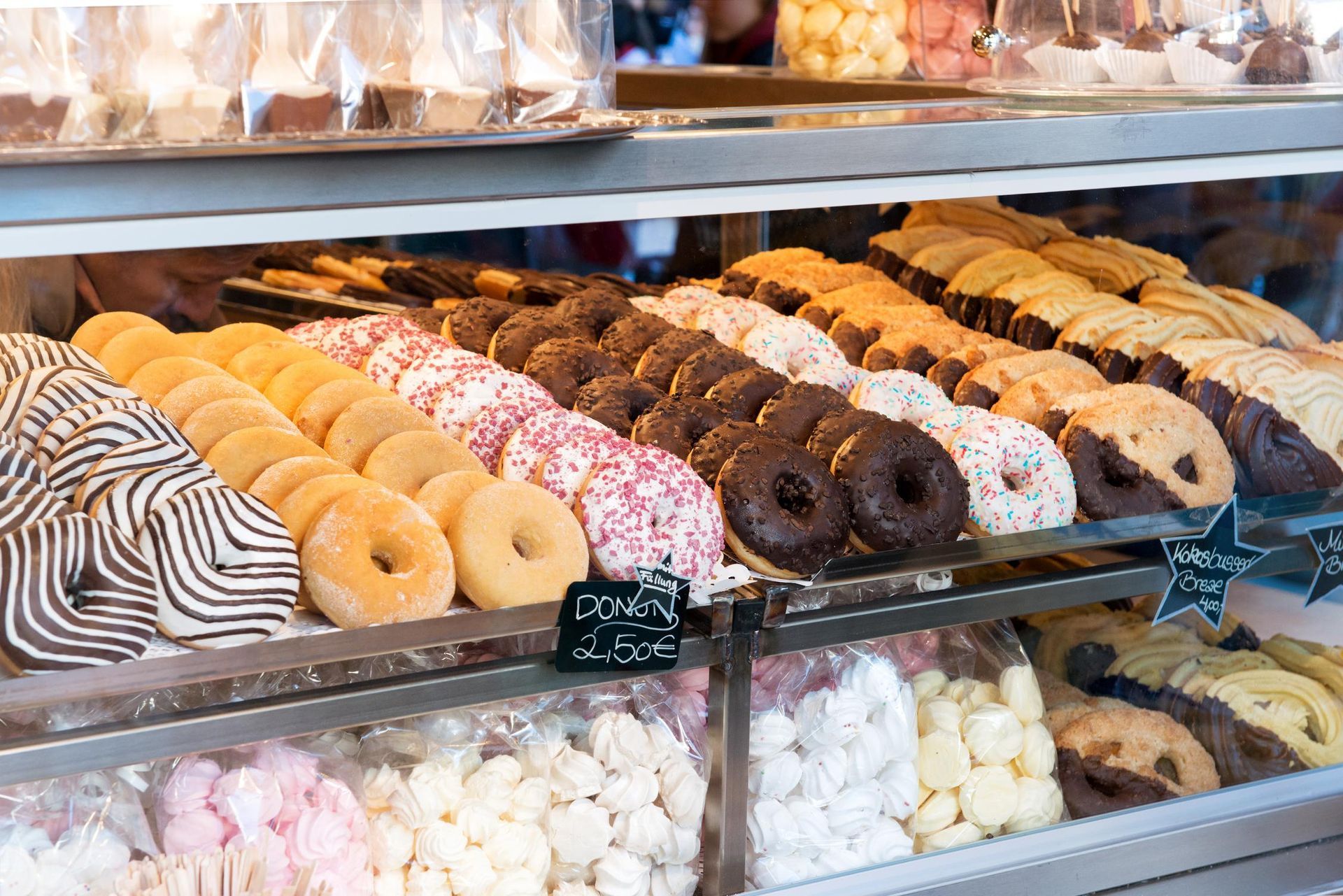 Donut display case with various colorful glazed donuts in a bakery.