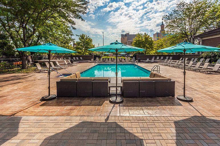 A large swimming pool surrounded by umbrellas and chairs at  Riley Towers, Indianapolis, IN. 