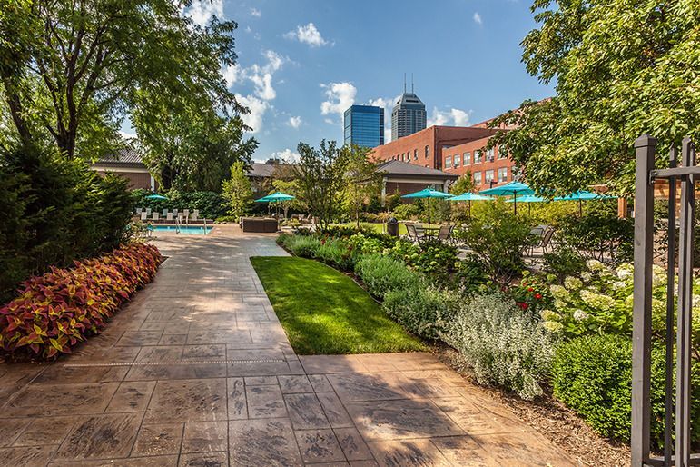 A walkway leading to a pool in a park with a city in the background at  Riley Towers, Indianapolis, IN. 