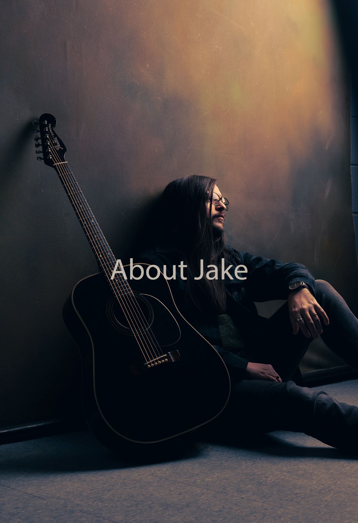 a portion of Jake Ackerman against a wall with a partial guitar showing