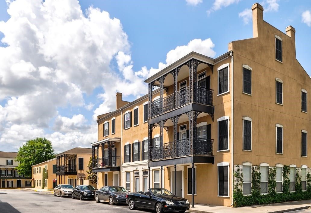 a row of buildings with cars parked in front of them .