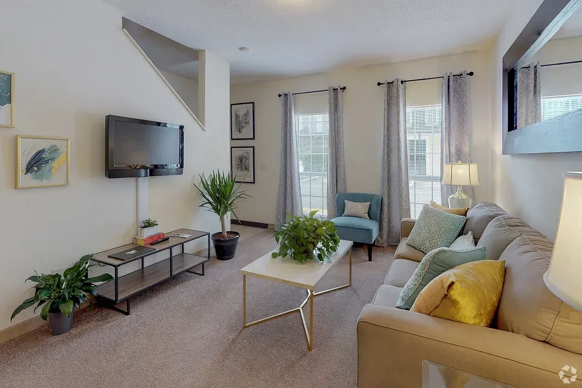 a living room with a couch , chair , coffee table and television .