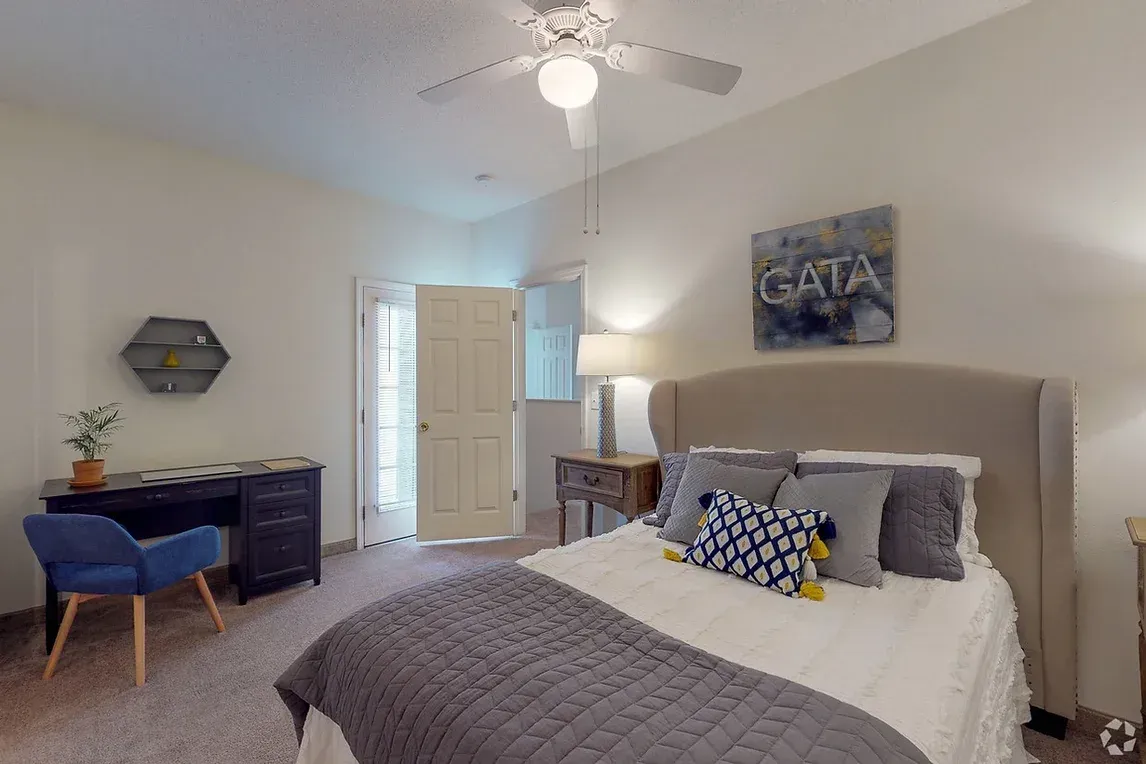 a bedroom with a bed , desk , chair and ceiling fan .