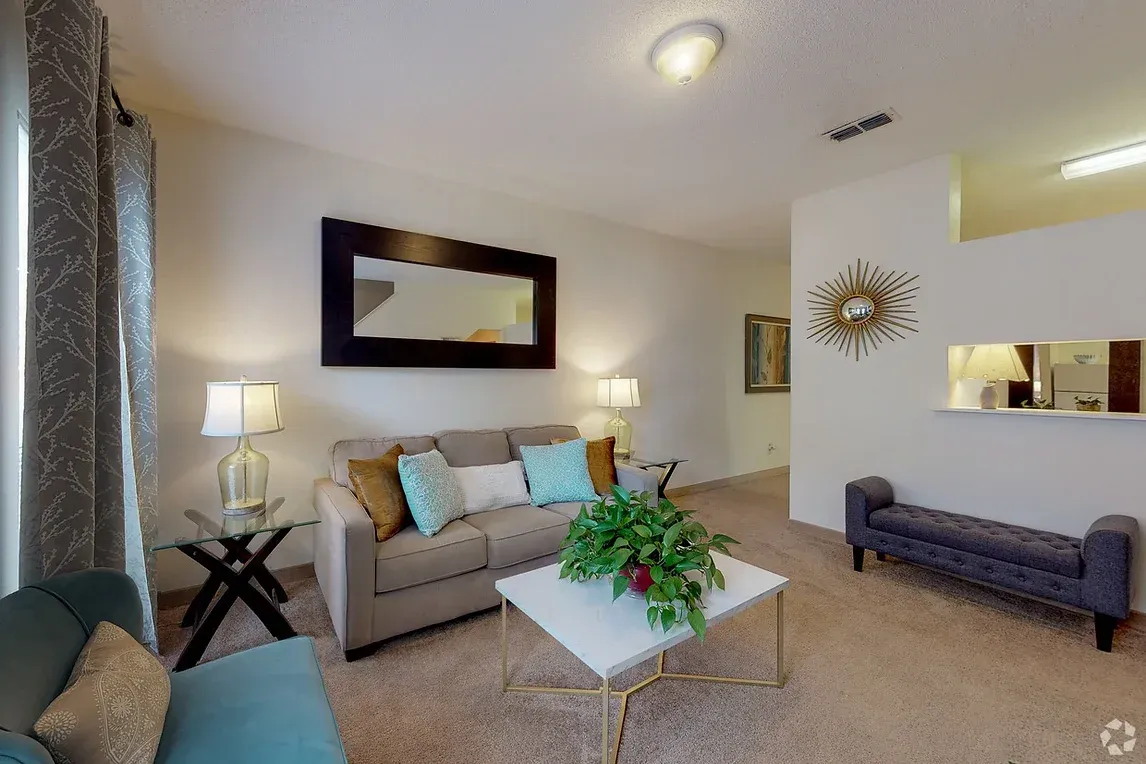 a living room with a couch , coffee table , bench and mirror .