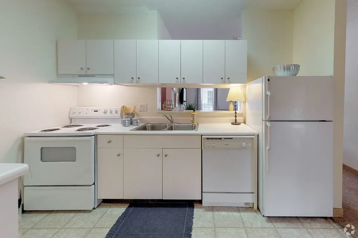 a kitchen with white cabinets , a stove , a refrigerator , and a sink .