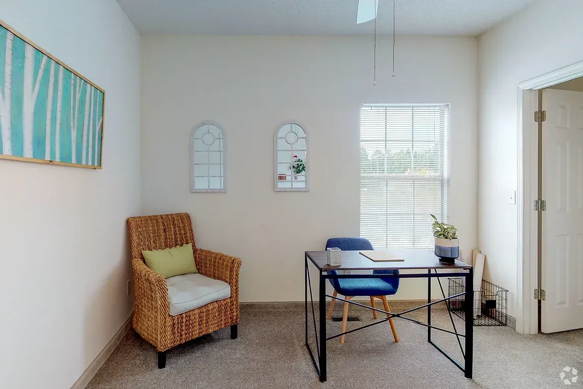 a room with a desk , chair , and window .