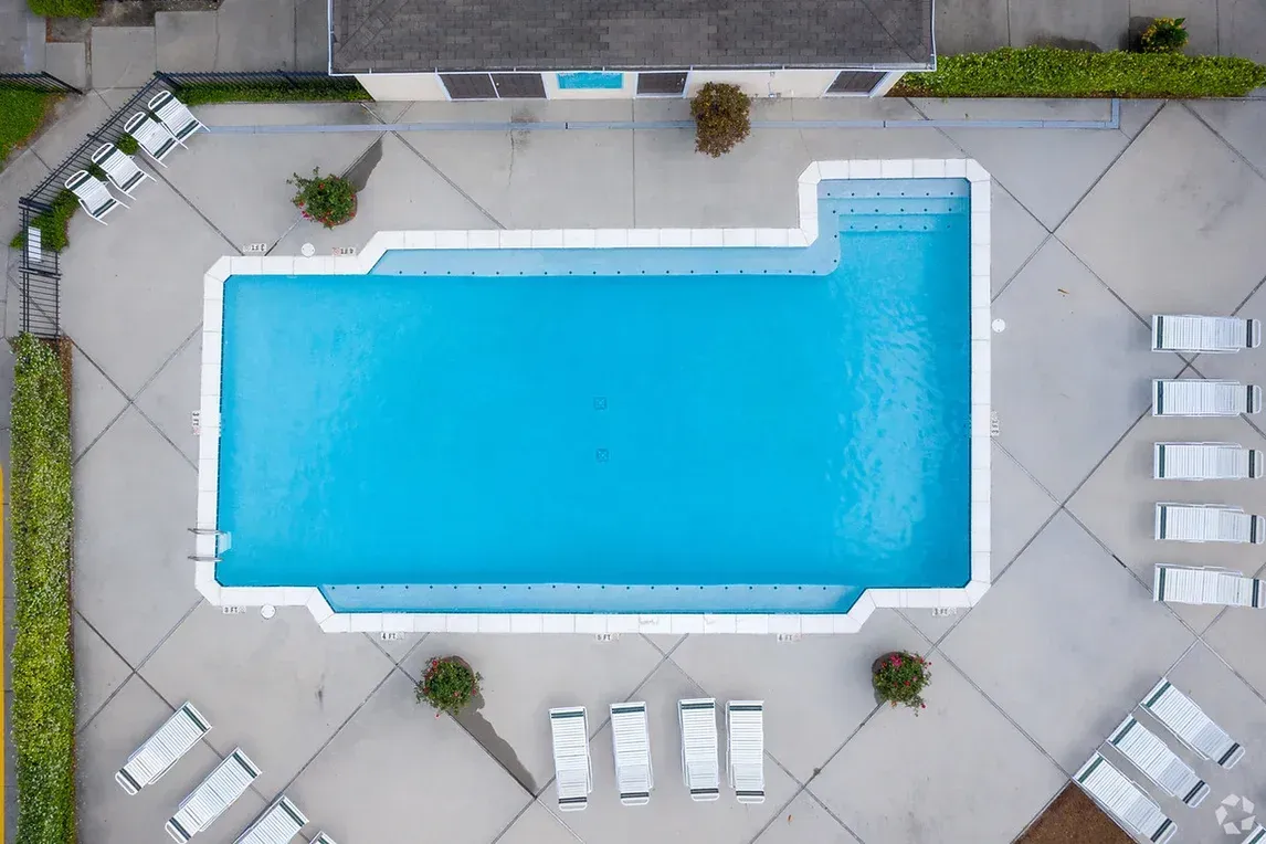 an aerial view of a large swimming pool with chairs around it .