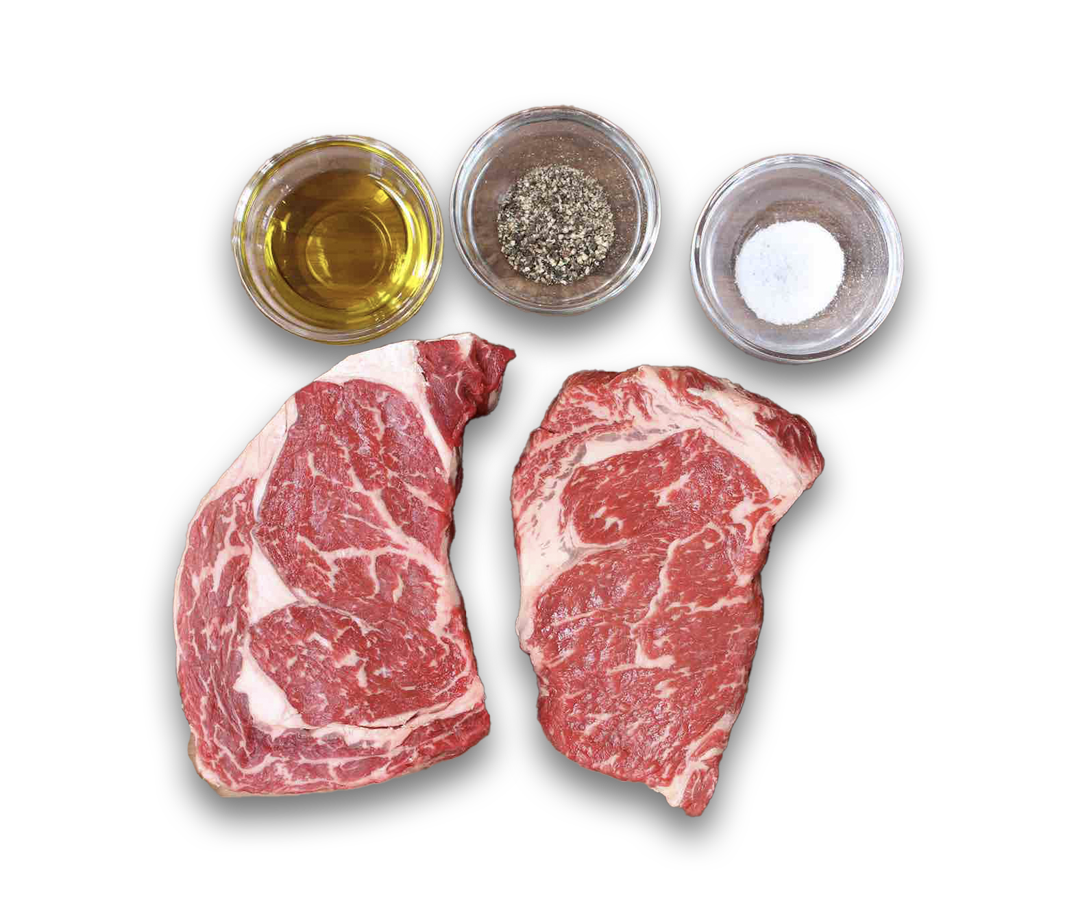 Two steaks are surrounded by bowls of oil salt and pepper.