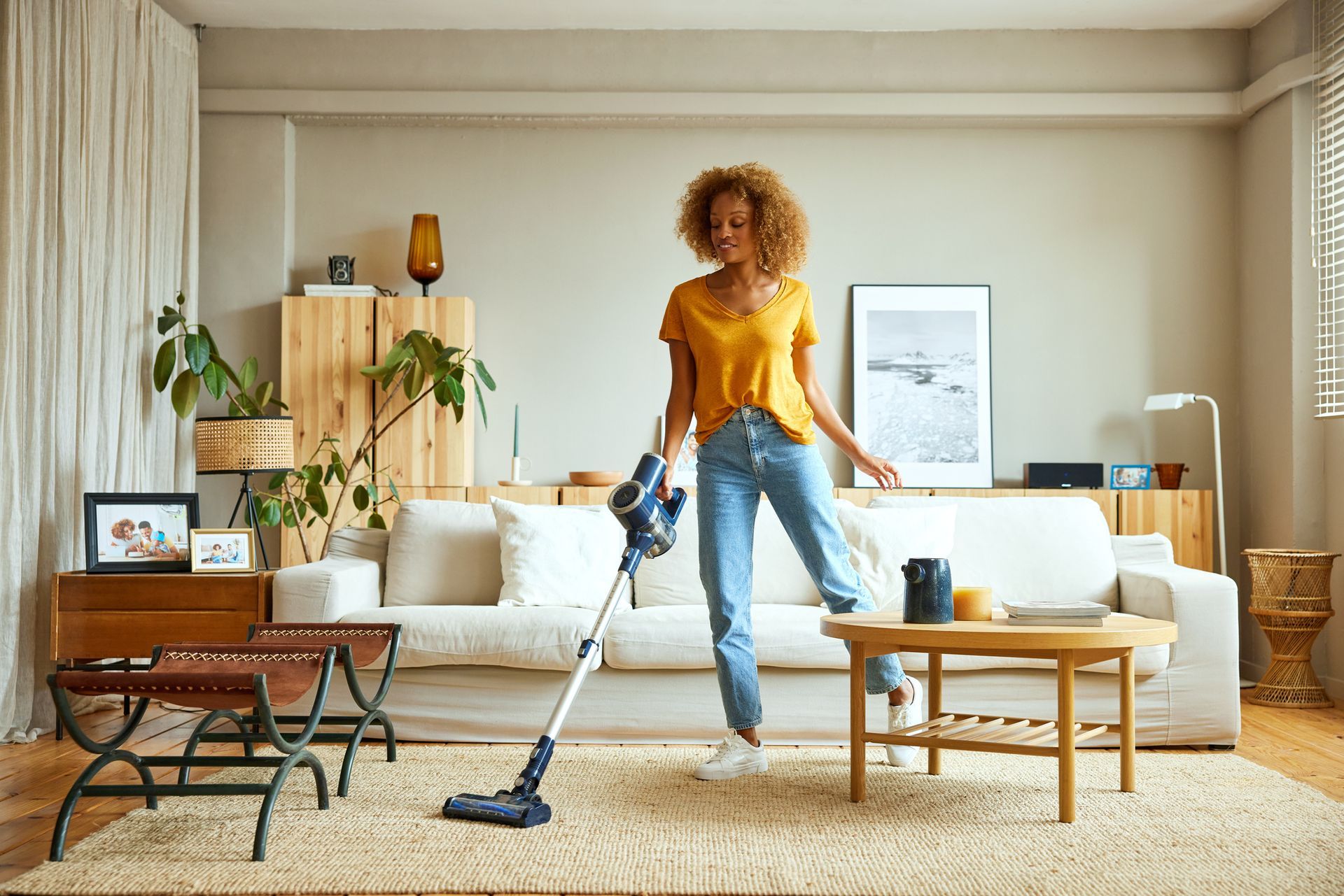 Woman cleaning carpet with vacuum cleaner at home