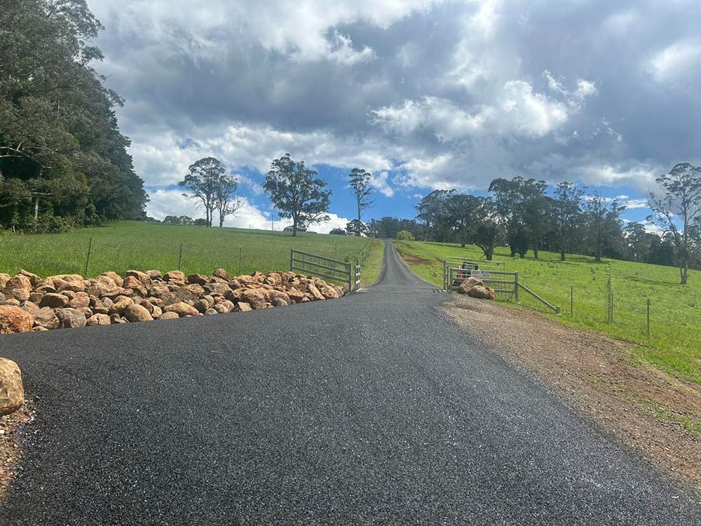 A Road Going Through a Grassy Field With Trees on the Side — North Coast Asphalts in Grafton, NSW