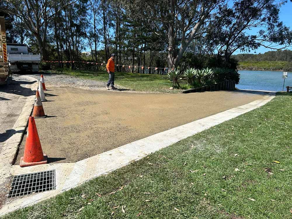 A Man is Walking Down a Sidewalk Next to a Lake — North Coast Asphalts in Clarence Valley, NSW