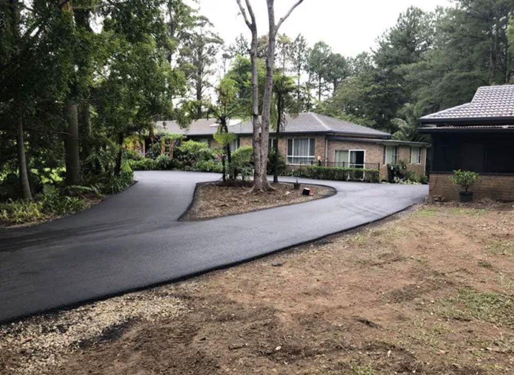 A Driveway Leading to a House Surrounded by Trees — North Coast Asphalts in Grafton, NSW
