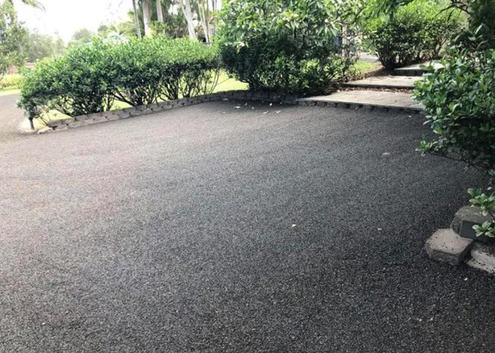 A Black Asphalt Driveway Surrounded by Trees and Bushes — North Coast Asphalts in Dorrigo, NSW