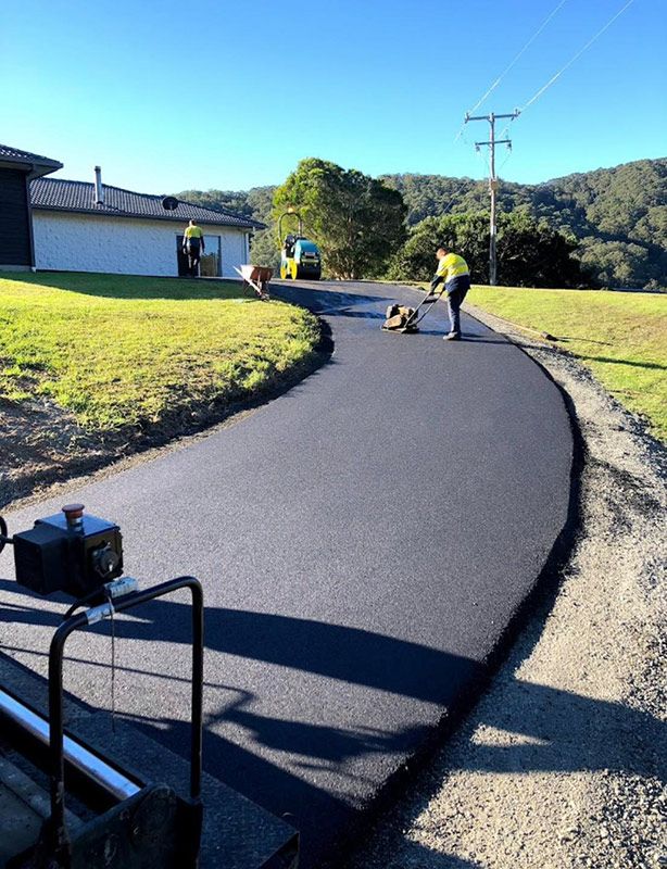 A Man is Laying Asphalt on the Side of a Road — North Coast Asphalts in Grafton, NSW