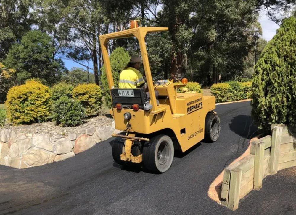 A Man is Driving a Yellow Forklift Down a Road — North Coast Asphalts in Corindi Beach, NSW